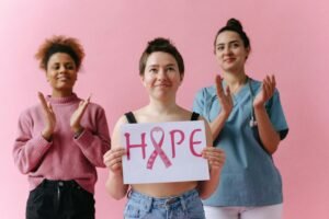 Three women show hope and support for breast cancer awareness, one holding a 'hope' sign.